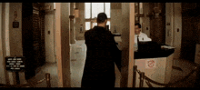 a man in a black coat is standing in front of a counter with a sign that says no smoking on it