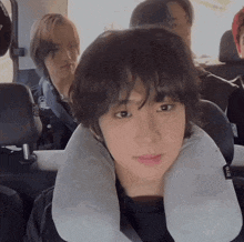 a person wearing a neck pillow with the word air on it looks at the camera