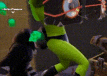 a cartoon character in a green suit and goggles is standing in a room .