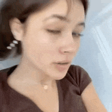 a close up of a woman 's face with her eyes closed and a necklace .