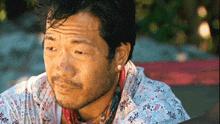 a man with a beard wearing a white shirt with flowers on it