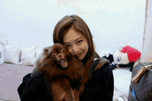 a woman holds a small brown dog in her arms