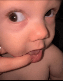 a close up of a baby 's face with a person holding it
