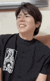 a man wearing a black t-shirt with the word academy on it smiles