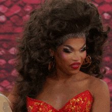 a woman wearing a red dress and gold hoop earrings with the word vogue on her lip