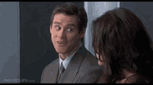 a man in a suit and tie is talking to a woman who is wearing glasses .