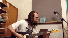 a man playing a guitar in front of a microphone