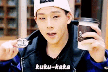 a young man holding a cup of coffee with kuku-kaka written on the bottom
