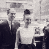 a man in a suit and tie smiles next to a woman in a dress