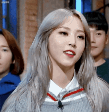 a woman with long gray hair is wearing a sweater and a red and white striped shirt .
