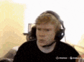 a man wearing headphones with a microphone on his head looks at the camera