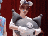 a man wearing a headband is holding a large stuffed animal .