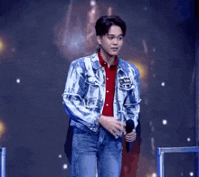 a young man in a denim jacket is holding a microphone and has a name tag on his jacket that says ' iris '