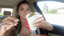 a woman is sitting in a car eating a mcdonald 's french fries