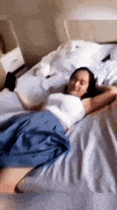 a woman in a blue skirt is laying on a bed with her arms outstretched .