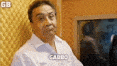 a man in a white shirt is making a funny face in a recording studio and the word gabbo is above him .