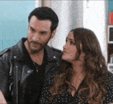 a man in a leather jacket and a woman in a polka dot dress are looking at each other