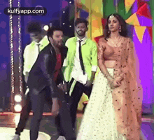 a group of people are standing next to each other on a stage in front of a colorful background .