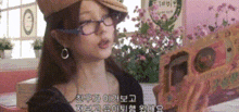 a woman wearing glasses and a hat is sitting in front of a picture frame .
