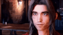 a man with long hair is standing in front of a table in a dark room .
