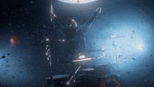 a man is playing drums in a dark room with his arms in the air
