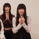 a girl with long black hair is smiling and holding a card with a picture of a girl on it