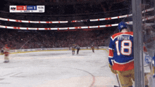 a hockey player with the number 18 on his jersey stands on the ice