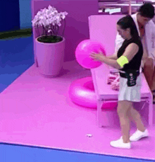 a woman is holding a pink balloon while standing on a pink mat .