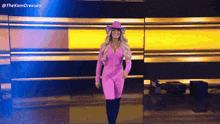 a woman in a pink outfit and cowboy hat is walking on a stage