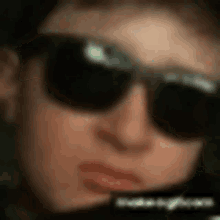 a close up of a person wearing sunglasses with a blurred background
