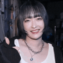 a woman wearing a necklace with a coin on it smiles for the camera