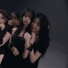 a group of young women in black dresses are dancing in a dark room
