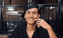 a young man wearing a black hat and a ring on his finger is smiling