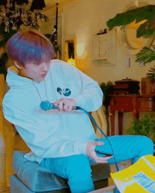 a person with purple hair is sitting on a couch playing a video game