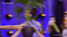 a group of people are dancing on a stage in front of a palm tree .