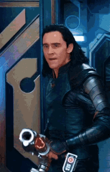 loki holding a gun in front of a door in a room .