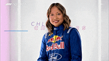 a woman wearing a blue red bull jacket is smiling