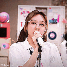 a girl wearing glasses is singing into a microphone while wearing a white shirt and tie