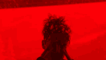 a man covering his face with his hands against a red background