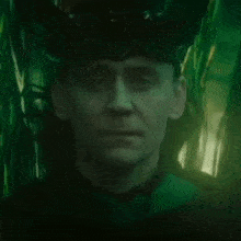 a close up of a man 's face in a dark room with a green light behind him .