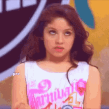 a close up of a girl making a funny face while wearing a pink and white shirt .