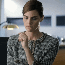 a woman in a black and white checkered jacket looks down at something