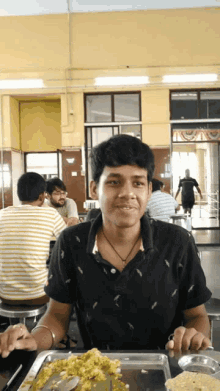 a man in a black shirt is sitting at a table with food