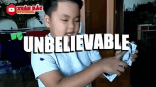 a young boy holding a playing card with the word unbelievable written on it