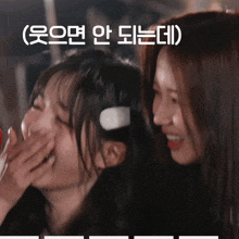 two girls are laughing and one has headphones on