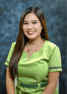 a woman wearing a green shirt with a necklace around her neck smiles for the camera
