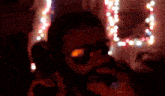 a blurry picture of a man with a beard and sunglasses in front of christmas lights