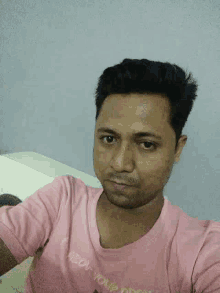 a man in a pink shirt is taking a picture of himself .