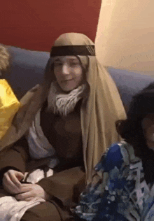 a person dressed as a shepherd is sitting on a couch with other people .
