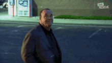 a man in a suit walks down a street with a sign that says bar rescue